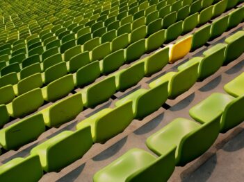 a yellow chair in rows of green chairs