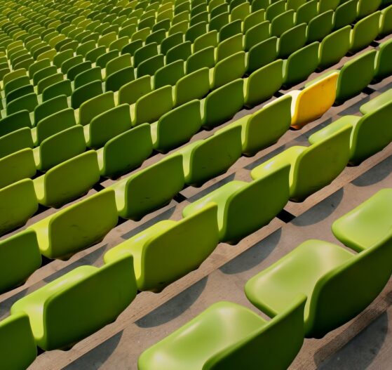a yellow chair in rows of green chairs